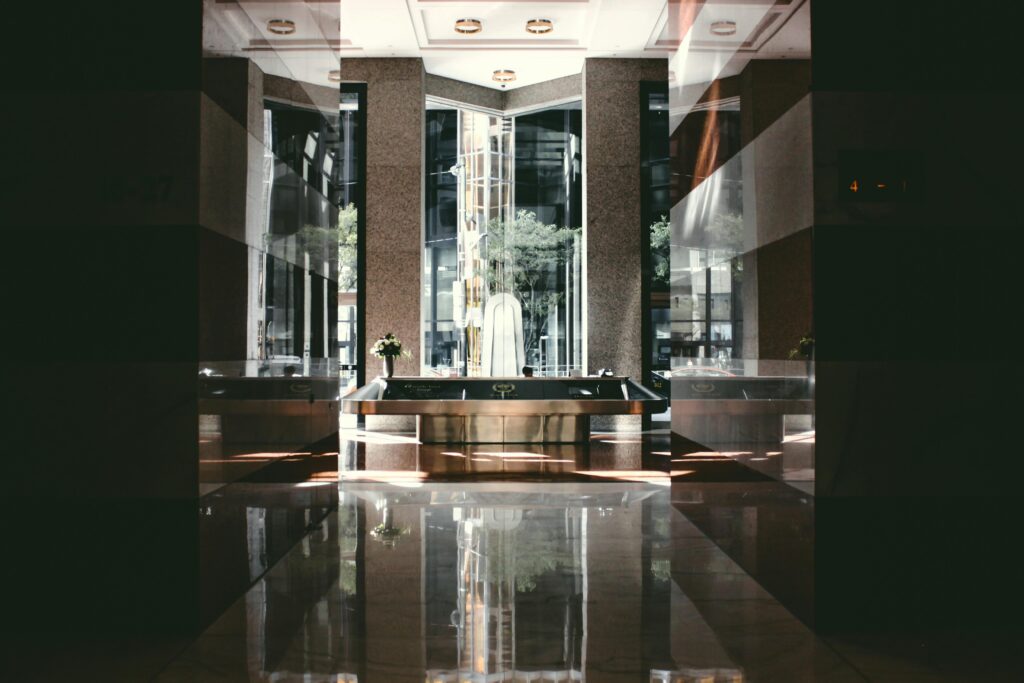 A sophisticated modern hotel lobby with glossy floors and natural light entering through large windows.