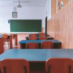 Home A tranquil empty classroom with wooden furniture and a green chalkboard, perfect for educational themes.