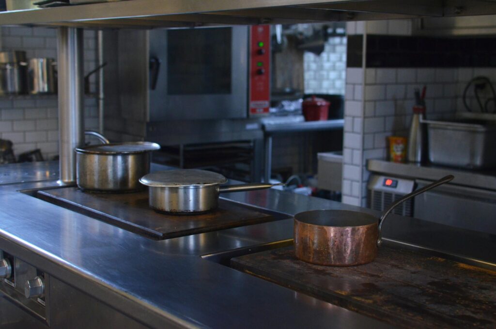 Stainless steel pots on a kitchen counter in a professional restaurant setting.